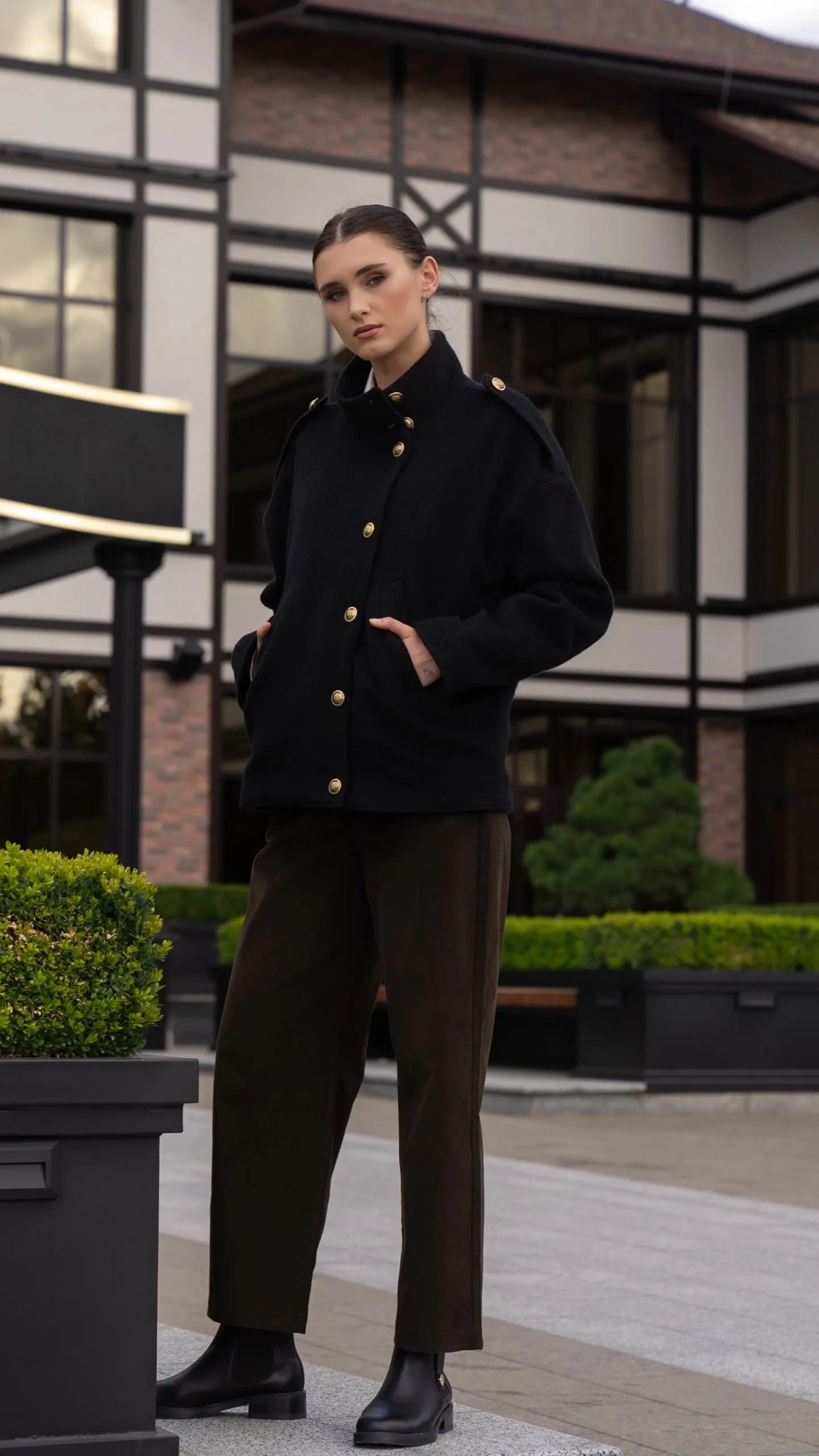 Модель з руками в кишенях, впевнений образ у темних відтінках