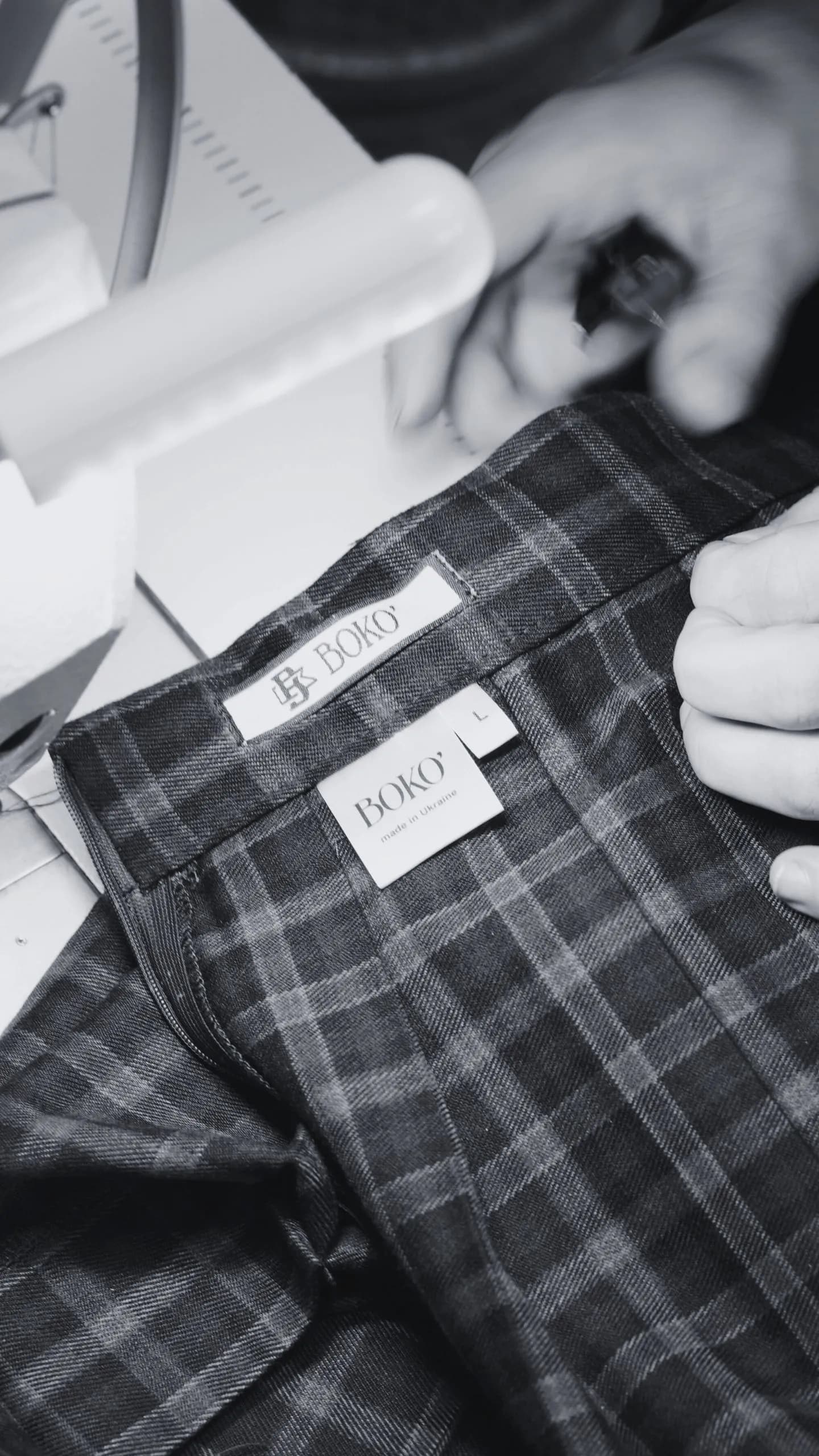 Крупний план бірок Boko на сірому картатому одязі, що підкреслює увагу до деталей.