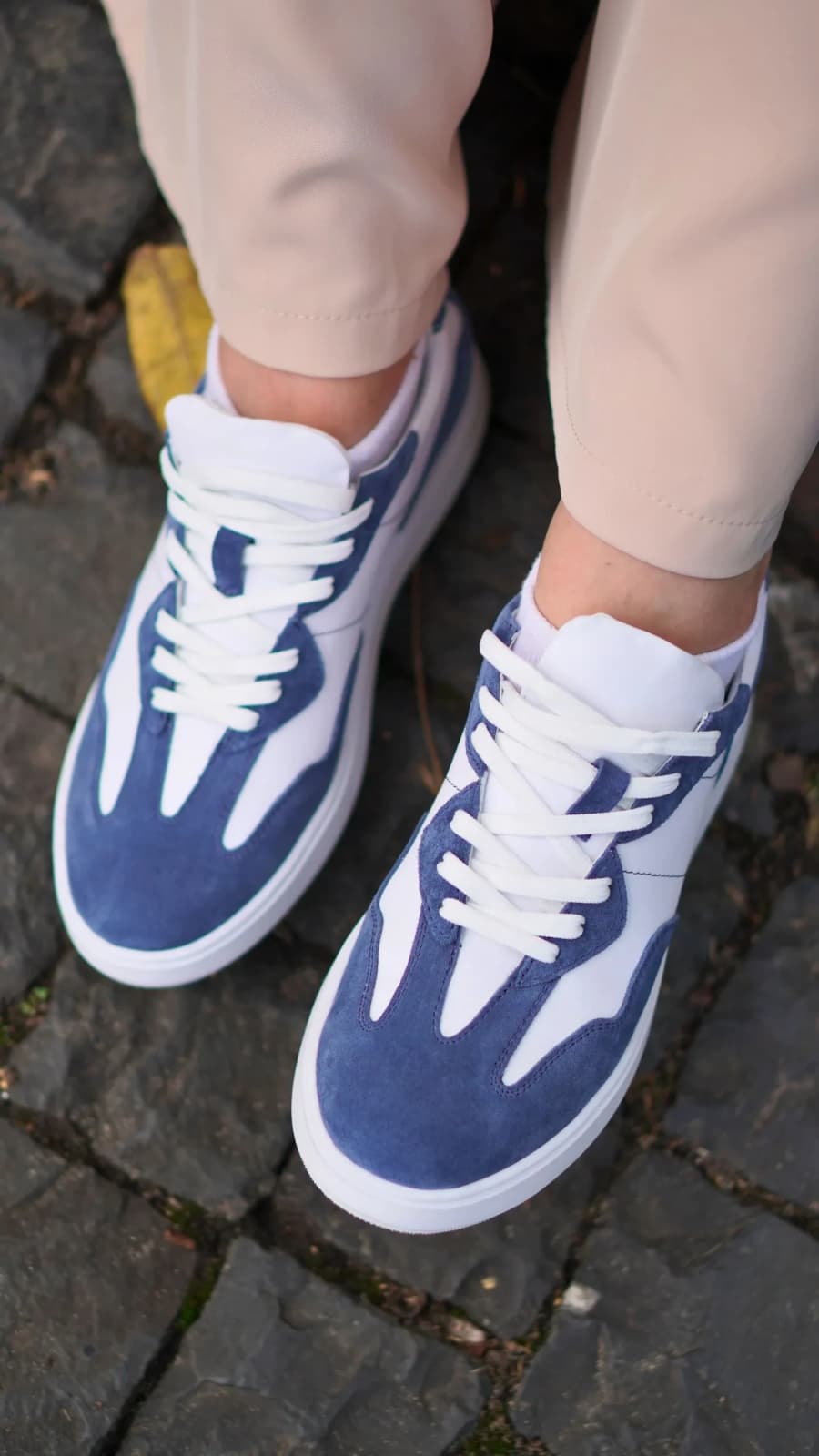 Синьо-білі кеди на нозі, крупний план шнурівки та замші на бруківці (зображення 1 з 5)